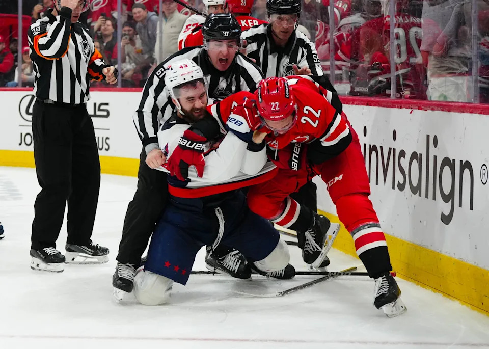 Apr 2, 2025; Raleigh, North Carolina, USA; Carolina Hurricanes center Logan Stankoven (22) and Washington Capitals right wing Tom Wilson (43) battle during the third period at Lenovo Center. Mandatory Credit: James Guillory-Imagn Images
