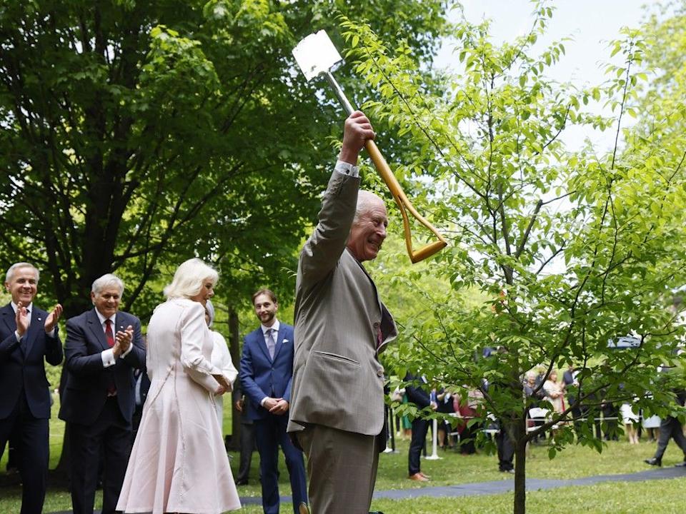 King Charles III holds a shovel as he participates with Queen Camilla in a ceremonial tree planting next to Prime Minister Mark Carney at Rideau Hall during an official two-day visit to Canada on May 26, 2025.