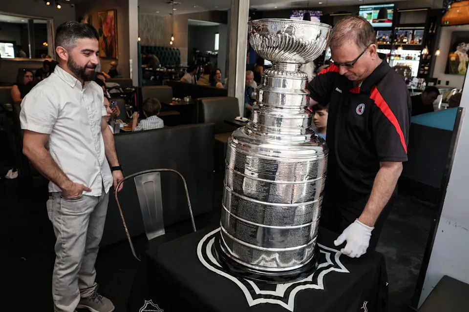 Nareg Dekermenjian, a teacher in Sherman Oaks, watches as Stanley Cup keeper Howie Borrow sets up the trophy.