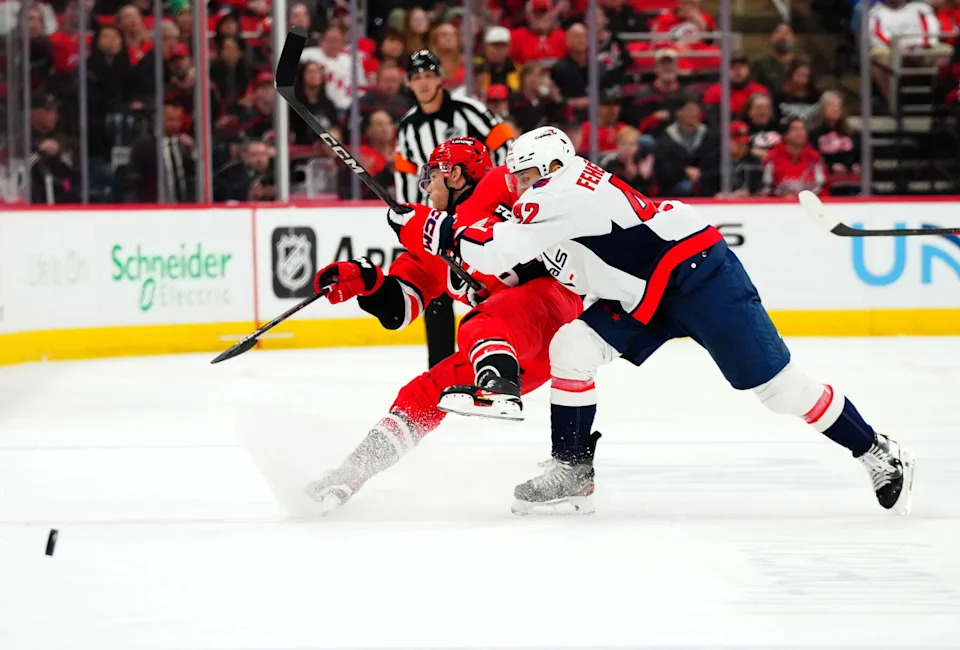 Apr 2, 2025; Raleigh, North Carolina, USA; Washington Capitals defenseman Martin Fehervary (42) checks Carolina Hurricanes center Mark Jankowski (77) during the first period at Lenovo Center. Mandatory Credit: James Guillory-Imagn Images