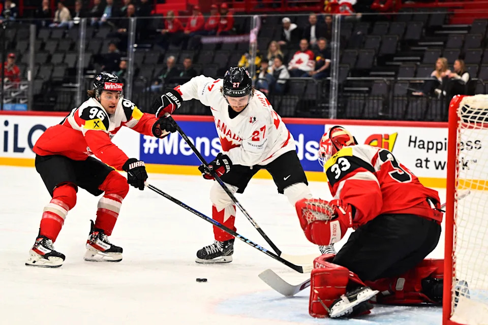 Austria forward Marco Kasper, Canada forward Barrett Hayton and Austria goalie Florian Vorauer vie for the puck during the IIHF Men's Ice Hockey World Championship Group A match between Canada and Austria at Avicii Arena in Stockholm, on May 15, 2025.