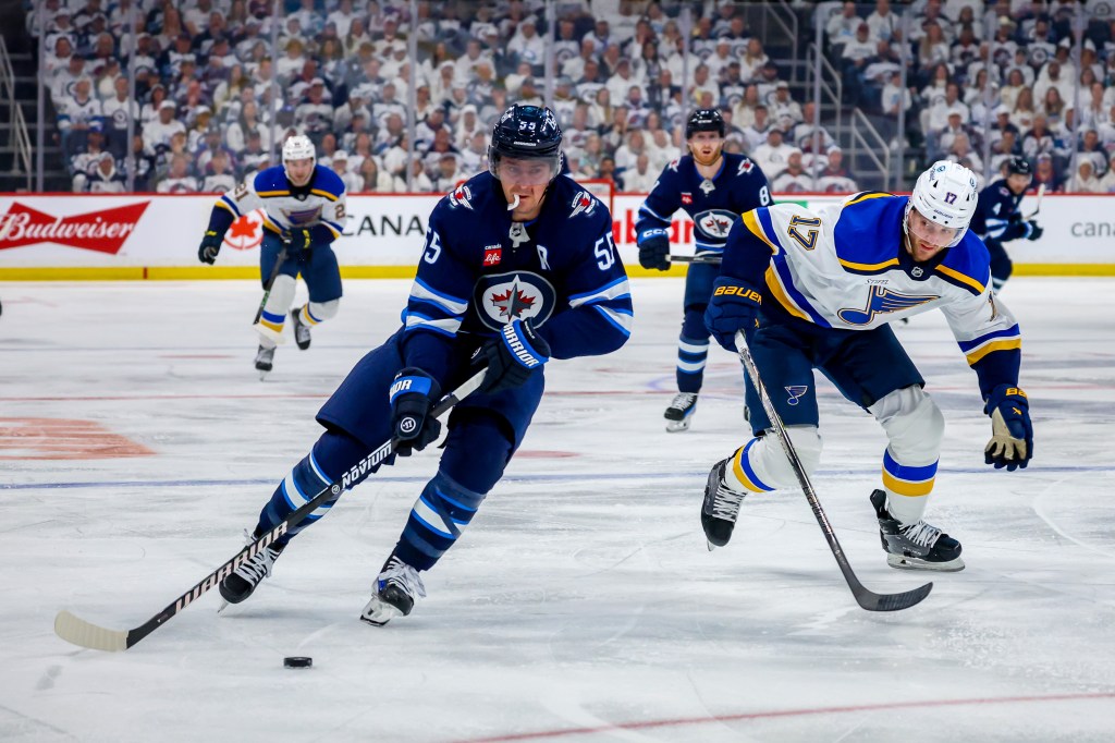 Mark Scheifele of the Winnipeg Jets plays the puck away from Cam Fowler of the St. Louis Blues during second-period action in Game Two of the First Round of the 2025 Stanley Cup Playoffs at Canada Life Centre on April 21, 2025.