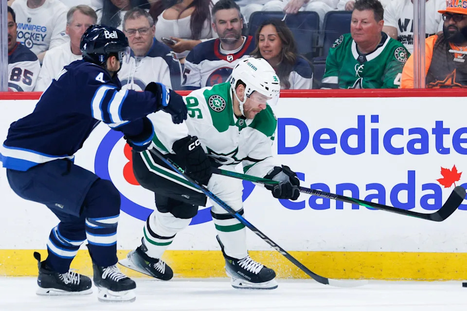 Dallas Stars forward Mikko Rantanen (96) tries to skate away from Winnipeg Jets defenseman Neal Pionk (4) at Canada Life Centre.Terrence Lee-Imagn Images