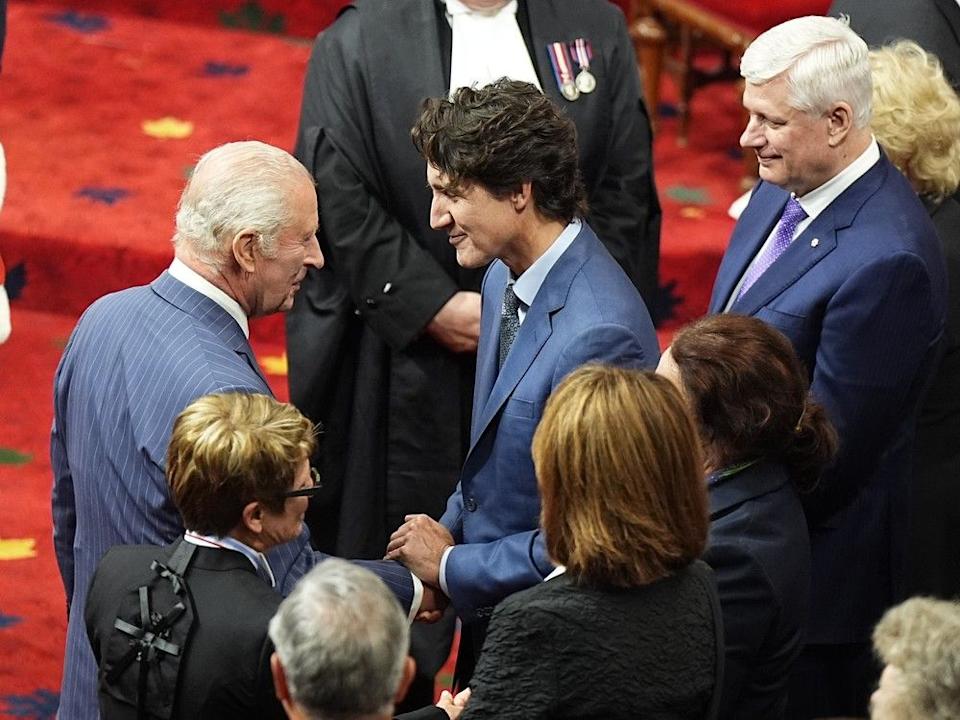 King Charles III speaks to former prime minister Justin Trudeau in the Senate Chamber for the opening of Parliament on Tuesday.