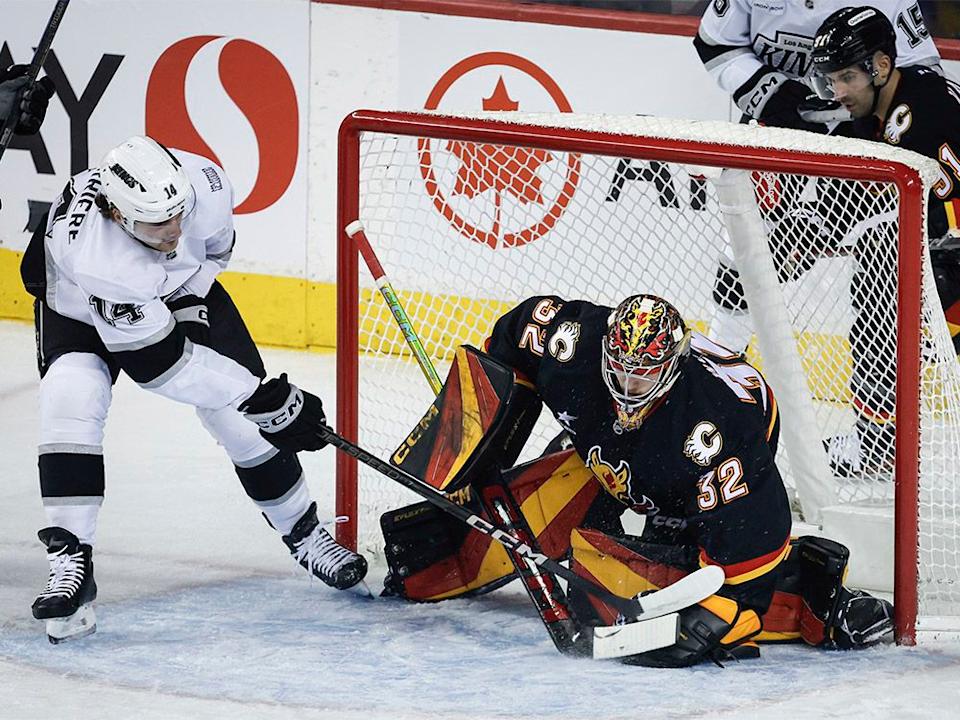  Los Angeles Kings’ Alex Laferriere, left, digs for the puck as Calgary Flames goalie Dustin Wolf covers it during first-period NHL action in Calgary on Saturday, Jan. 11, 2025.