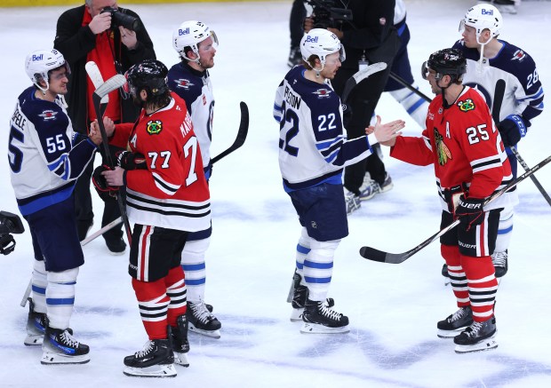 Blackhawks left wing Patrick Maroon (77) and defenseman Alec Martinez (25) share a moment with Jets players after a shootout loss on April 12, 2025, at the United Center. Both players are retiring. (Chris Sweda/Chicago Tribune)
