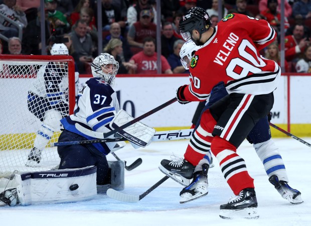 Jets goaltender Connor Hellebuyck blocks a shot from Blackhawks center Joe Veleno in the third period on April 12, 2025, at the United Center. (Chris Sweda/Chicago Tribune)