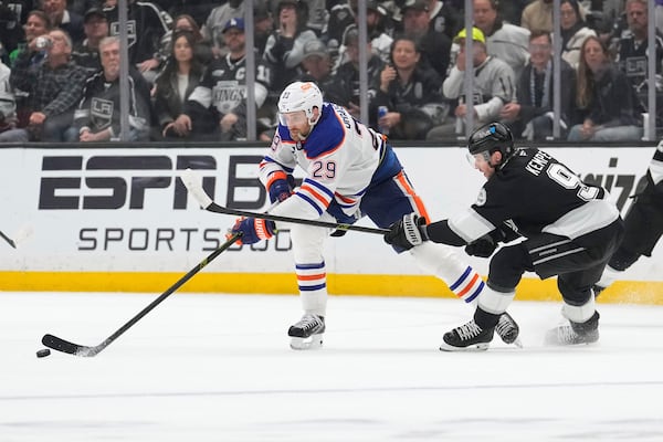 Edmonton Oilers center Leon Draisaitl, left, passes the puck while under pressure from Los Angeles Kings right wing Adrian Kempe during the third period in Game 5 of an NHL hockey first-round playoff series Tuesday, April 29, 2025, in Los Angeles. (AP Photo/Mark J. Terrill)