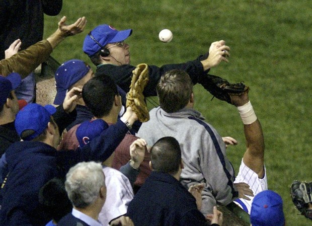 Chicago Cubs left fielder Moises Alou's arm is seen reaching into the stands, right, unsuccessfully for a foul ball as fan Steve Bartman deflects the ball, at top, in the eighth inning during Game 6 of the National League championship series against the Florida Marlins on Oct. 14, 2003, at Wrigley Field.