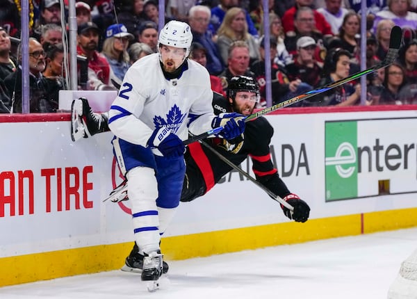 Ottawa Senators' Michael Amadio, right, is knocked off his skates after a hit into the boards by Toronto Maple Leafs' Simon Benoit (2) during the second period of Game 6 of a first-round NHL hockey playoff series in Ottawa, Ontario, Thursday, May 1, 2025. (Justin Tang/The Canadian Press via AP)