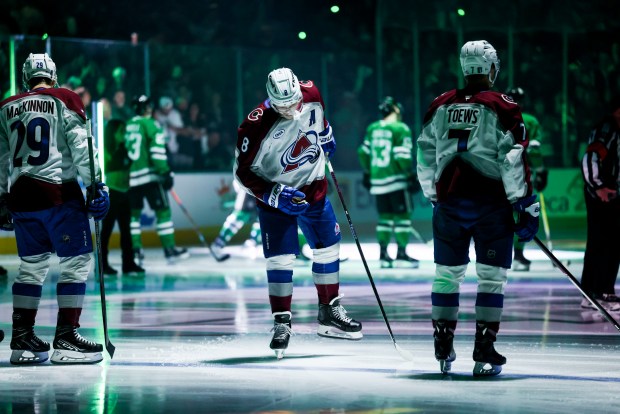 Colorado Avalanche players Nathan MacKinnon (29), Cale Makar (8) and Devon Toews (7) line up for the national anthem before a first-round NHL hockey playoff game against the Dallas Stars in Dallas, Saturday, April 19, 2025. (AP Photo/Gareth Patterson)