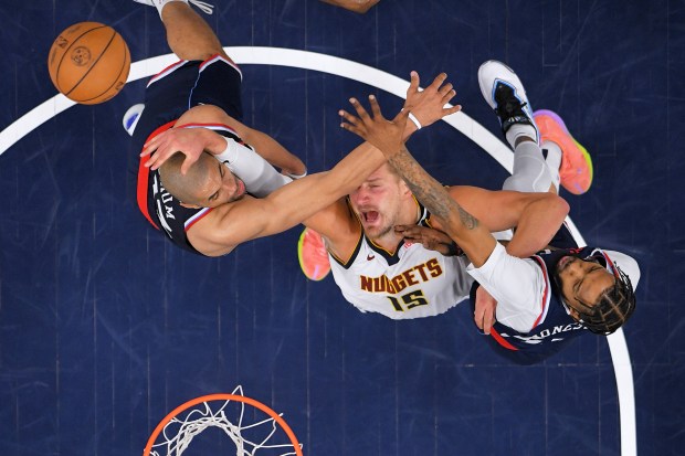 Los Angeles Clippers forward Nicolas Batum, left, and forward Derrick Jones Jr., right, reach for a rebound along with Denver Nuggets center Nikola Jokic during the second half in Game 6 of an NBA basketball first-round playoff series Thursday, May 1, 2025, in Inglewood, Calif. (AP Photo/Mark J. Terrill)