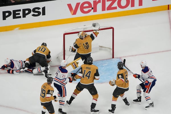 Vegas Golden Knights goaltender Adin Hill (33) reaches for the puck during the second period of Game 1 of a second-round NHL hockey playoff series against the Edmonton Oilers, Tuesday, May 6, 2025, in Las Vegas. (AP Photo/John Locher)