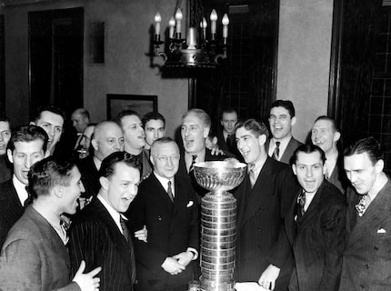 Members of the New York Rangers are posing with the Stanley Cup, which they won by defeating...
