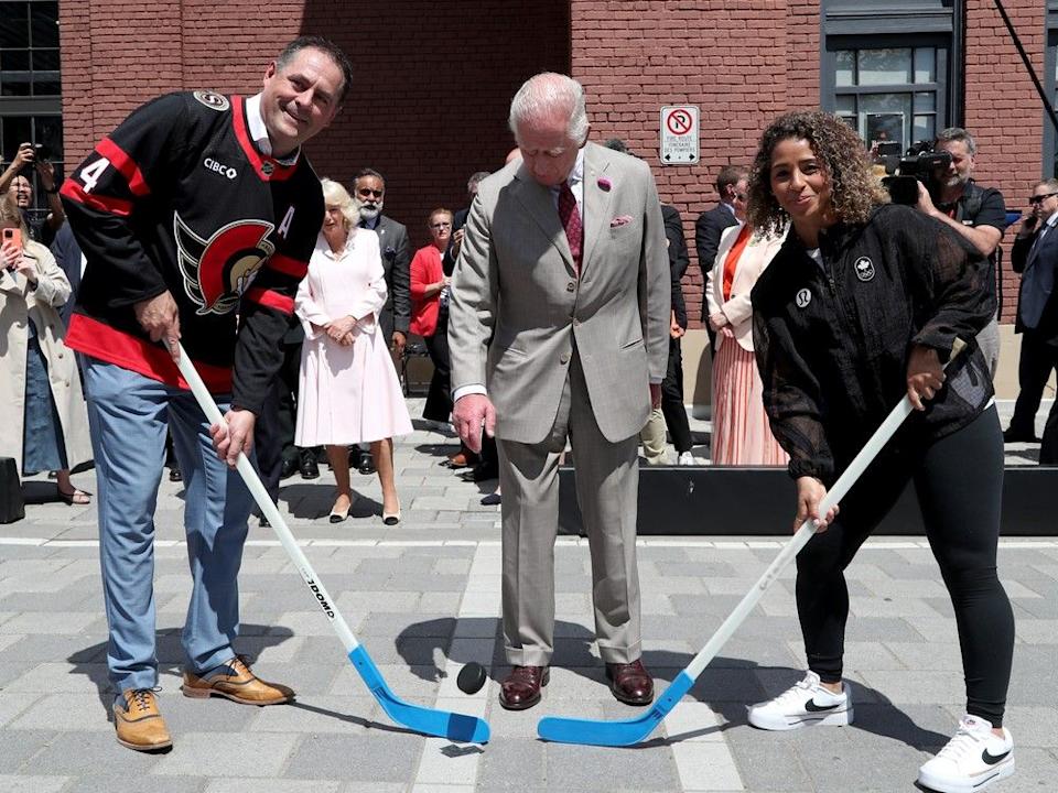 King Charles officially drops the puck for an outdoor hockey game. Taking the faceoff are former Ottawa Senators defenceman Chris Phillips and Olympic soccer gold medallist Desiree Scott, who plays for the Ottawa Rapid FC.