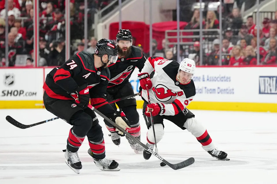 Apr 20, 2025; Raleigh, North Carolina, USA; New Jersey Devils left wing Jesper Bratt (63) controls the puck against Carolina Hurricanes defenseman Jaccob Slavin (74) during the second period of game one of the first round of the 2025 Stanley Cup Playoffs at Lenovo Center. Mandatory Credit: James Guillory-Imagn Images