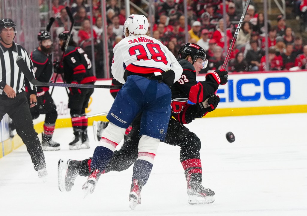Washington's Rasmus Sandin and Carolina's Jackson Blake battle for a puck during Game 3.