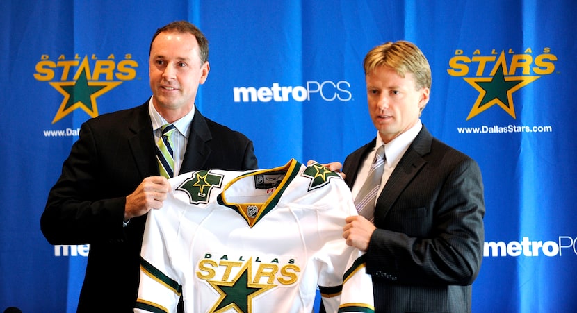 Dallas Stars general manager Joe Nieuwendyk (left) holds up a Stars jersey with new head...