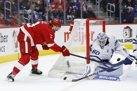 Detroit Red Wings defenseman Justin Holl attempting a wrap-around attempt against Toronto Maple Leafs goaltender Joseph Woll.