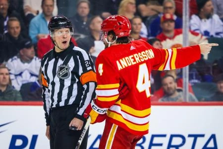 Calgary Flames defenseman Rasmus Andersson talking to a referee.