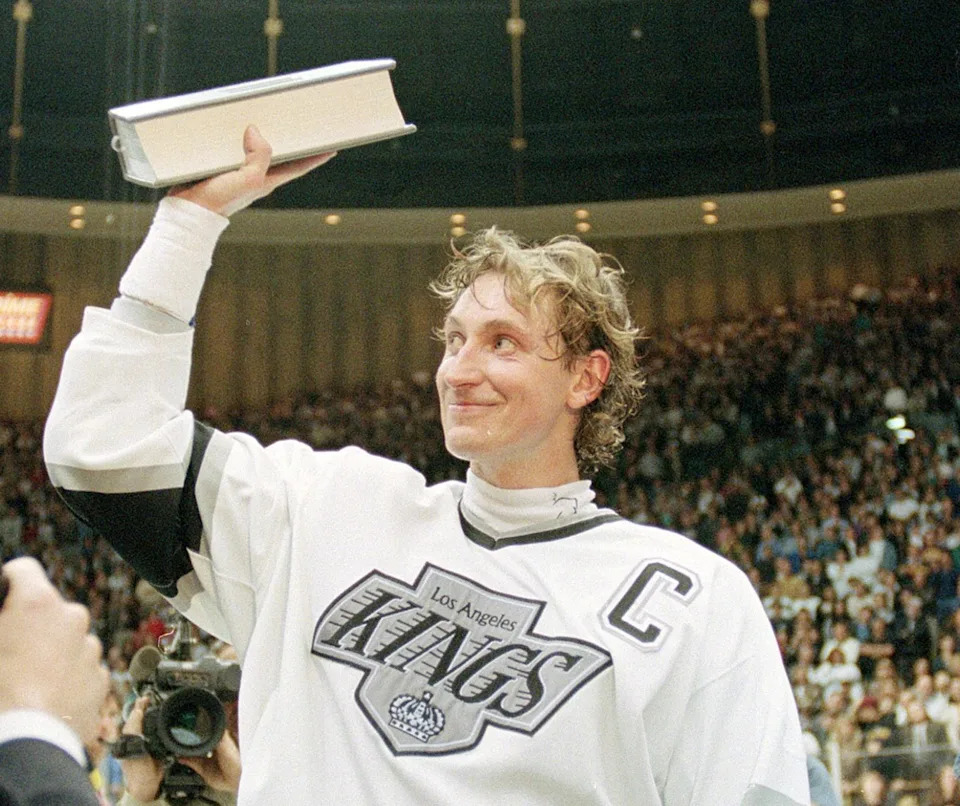 Los Angeles Kings' Wayne Gretzky waves a record book listing his career goals, presented to him after he set a new NHL career-goal record with his 802nd goal against the Vancouver Canucks, on March 23, 1994