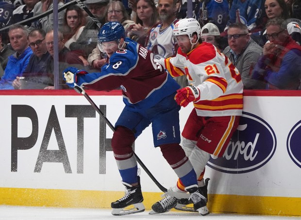 Colorado Avalanche defenseman Cale Makar, left, checks Calgary Flames center Kevin Rooney in the second period of an NHL hockey game Monday, March 31, 2025, in Denver. (AP Photo/David Zalubowski)
