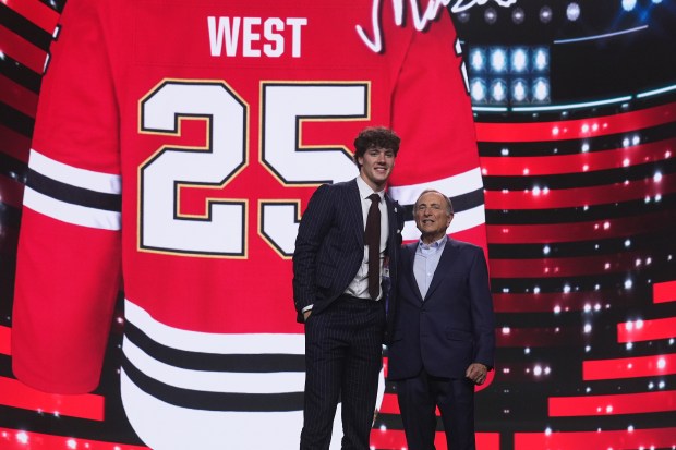 Mason West, left, stands with NHL commissioner Gary Bettman after being drafted by the Chicago Blackhawks during the NHL hockey draft Friday, June 27, 2025, in Los Angeles. (AP Photo/Damian Dovarganes)