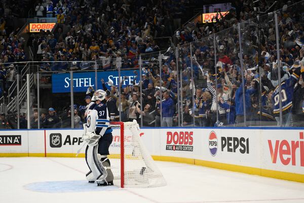 St. Louis Blues fans react as Winnipeg Jets goaltender Connor Hellebuyck (37) looks on during the second period in Game 6 of an NHL hockey first-round playoff series against the Winnipeg Jets, Friday, May 2, 2025, in St. Louis. (AP Photo/Jeff Le)