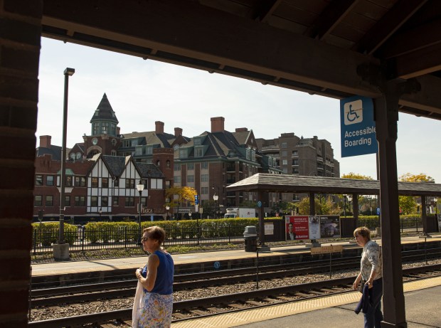 Riders wait for a Metra train at the station in...