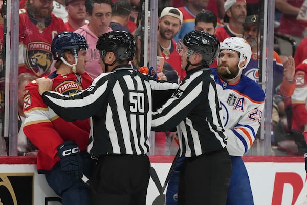 NHL referees separate Florida Panthers center Anton Lundell (15) and Edmonton Oilers center Leon Draisaitl (29) during the first period of Game 3 of the NHL Stanley Cup final Monday, June 9, 2025, in Sunrise, Fla. (AP Photo/Lynne Sladky)