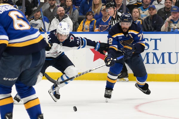 St. Louis Blues defenseman Justin Faulk, right, pressures Winnipeg Jets center Cole Perfetti (91) during the first period in Game 6 of an NHL hockey first-round playoff series Friday, May 2, 2025, in St. Louis. (AP Photo/Jeff Le)