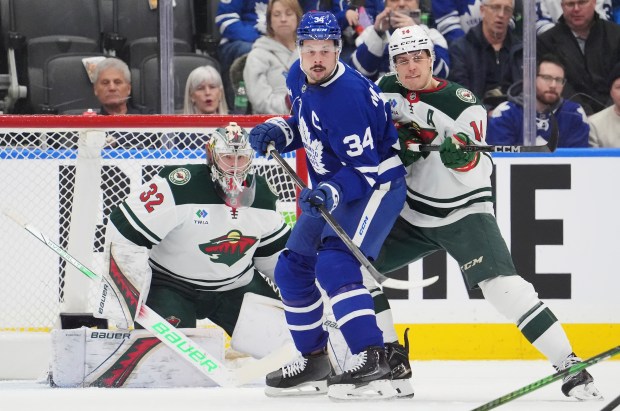 Toronto Maple Leafs' Auston Matthews (34) and Minnesota Wild's Joel Eriksson Ek battle in front of Wild goaltender Filip Gustavsson (32) during the first period of an NHL hockey game in Toronto on Wednesday, Jan. 29, 2025. (Frank Gunn/The Canadian Press via AP)
