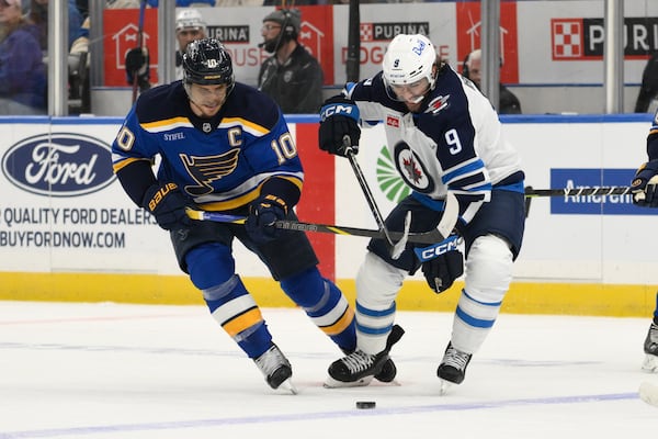St. Louis Blues center Brayden Schenn, left, battles Winnipeg Jets left wing Alex Iafallo, right, during the first period in Game 6 of an NHL hockey first-round playoff series Friday, May 2, 2025, in St. Louis. (AP Photo/Jeff Le)