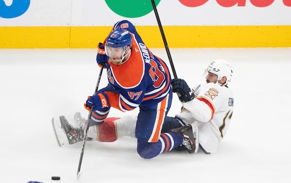 Florida Panthers' Sam Reinhart (13) and Edmonton Oilers' Connor McDavid (97) battle for the puck during the third period in Game 5 of the NHL hockey Stanley Cup Final in Edmonton, Alberta, Saturday, June 14, 2025. ( Jason Franson/The Canadian Press via AP)