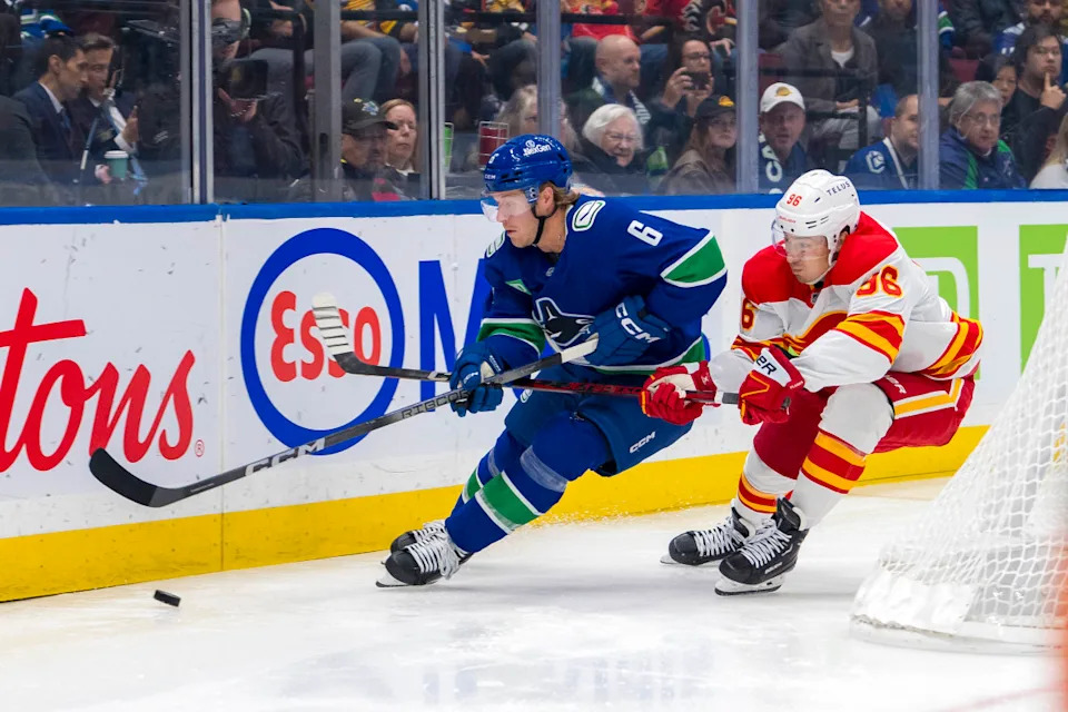 Flames forward Andrei Kuzmenko stick checks Canucks forward Brock Boeser.Bob Frid-Imagn Images