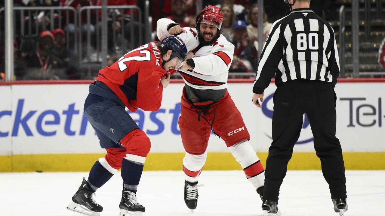 Washington Capitals right wing Brandon Duhaime (22) and Carolina Hurricanes defenseman Jalen Chatfield, center, fight during the first period of an NHL hockey game, Thursday, April 10, 2025, in Washington. (AP Photo/Nick Wass)
