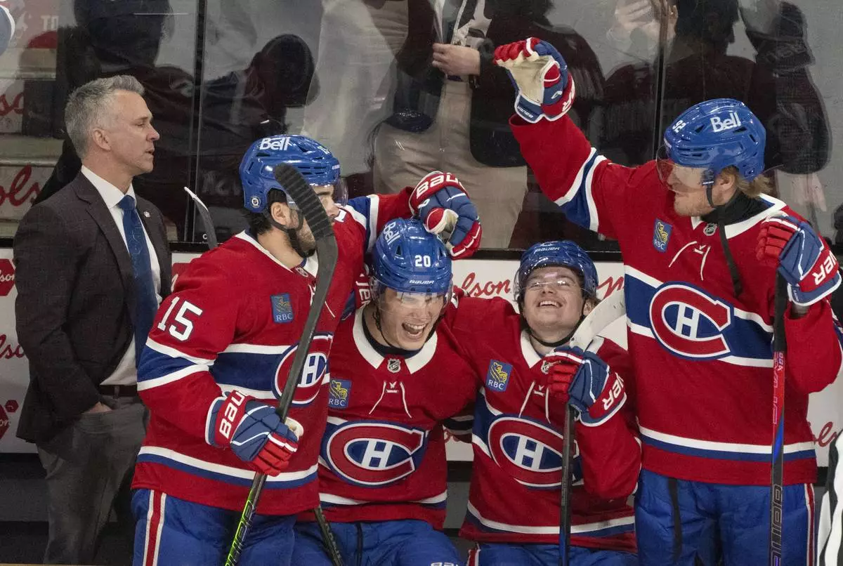 Montreal Canadiens head coach Martin St. Louis looks on as Alex Newhook (15), Juraj Slafkovsky (20), Cole Caufield (13) and Patrik Laine (92) celebrate their win in the final minutes of play against the Carolina Hurricanes during third period NHL hockey action in Montreal on Wednesday, April 16, 2025. (Christinne Muschi/The Canadian Press via AP)