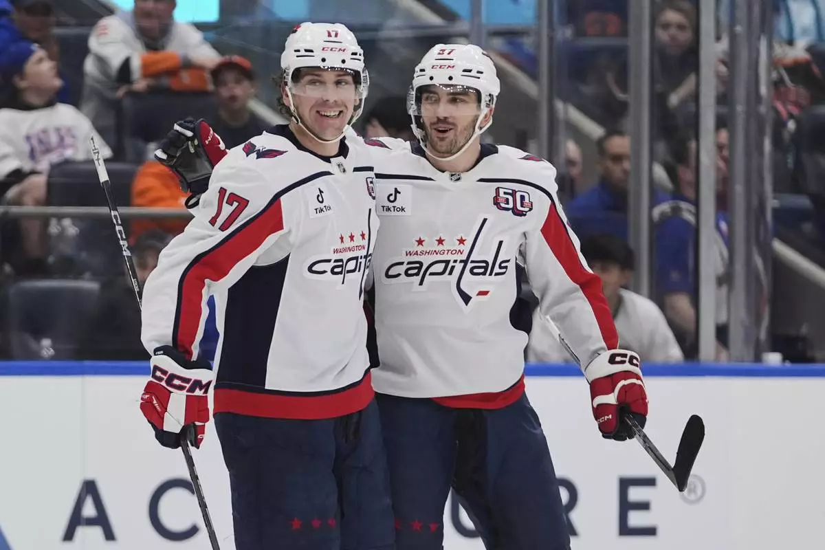 Washington Capitals' Dylan Strome (17) celebrates with teammate Trevor van Riemsdyk (57) after scoring an empty-net goal during the third period of an NHL hockey game against the New York Islanders Tuesday, April 15, 2025, in Elmont, N.Y. (AP Photo/Frank Franklin II)