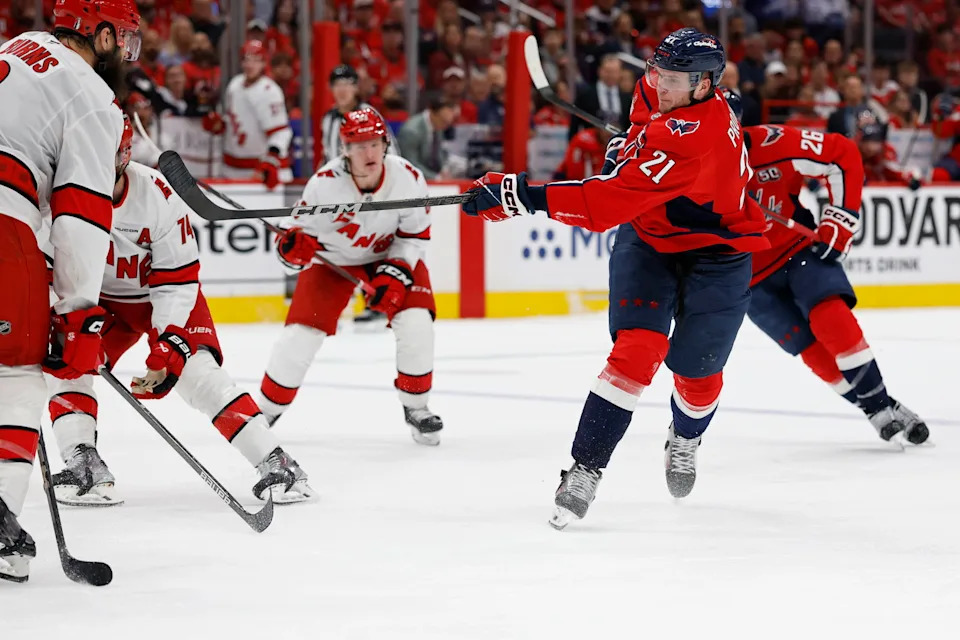 May 6, 2025; Washington, District of Columbia, USA; Washington Capitals center Aliaksei Protas (21) shoots the puck as Carolina Hurricanes defenseman Brent Burns (8) defends in the third period in game one of the second round of the 2025 Stanley Cup Playoffs at Capital One Arena. Mandatory Credit: Geoff Burke-Imagn Images