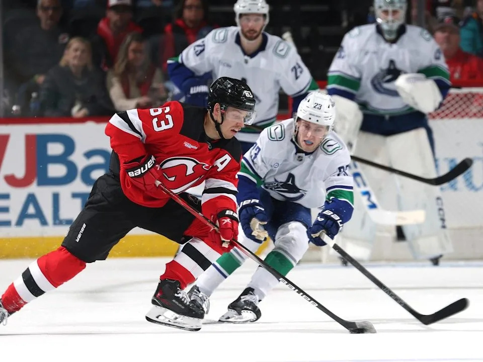  Jesper Bratt of New Jersey Devils is pressured by Canucks rookie Jonathan Lekkerimäki on March 24, 2025 in Newark, N.J.