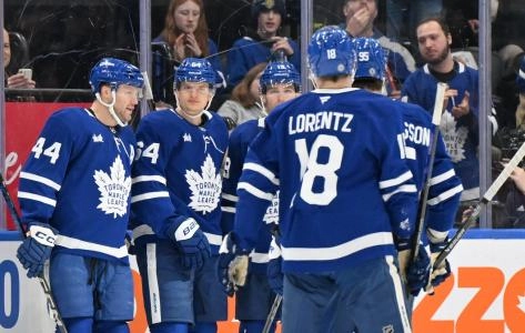 David Kampf, Pontus Holmberg, and Morgan Rielly among several Maple Leafs players celebrating a goal being scored. David Kampf, Pontus Holmberg, and Morgan Rielly among several Maple Leafs players celebrating a goal being scored.