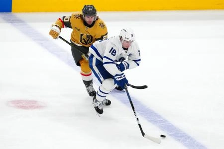Toronto Maple Leafs forward Mitch Marner being hooked by Vegas Golden Knights forward Brandon Saad.