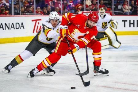 Calgary Flames forward Nazem Kadri protecting the puck against Vegas Golden Knights defenseman Zach Whitecloud.