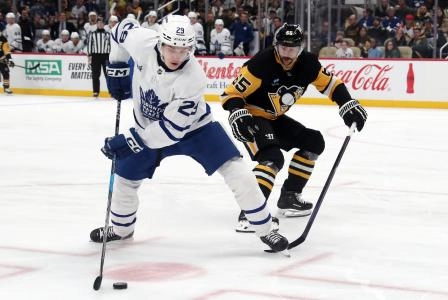 Toronto Maple Leafs forward Matthew Knies protecting the puck against Pittsburgh Penguins defenseman Erik Karlsson.