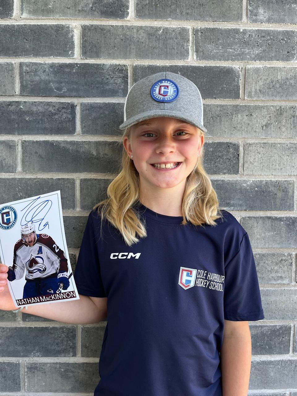 Rosie Tanner, 10, shows off the signed photo of Nathan MacKinnon she received on her last day at hockey camp.