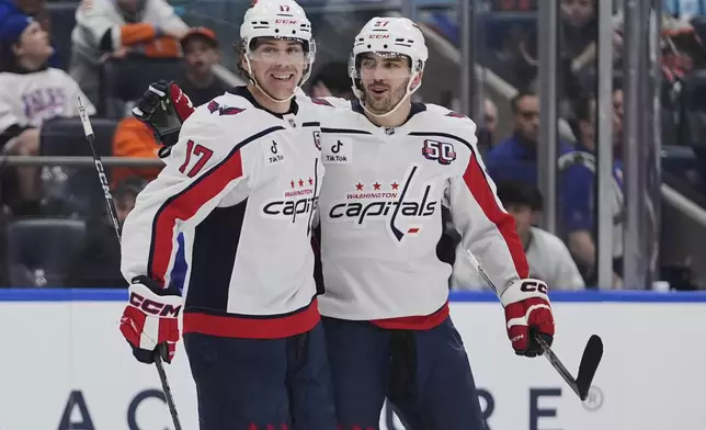 Washington Capitals' Dylan Strome (17) celebrates with teammate Trevor van Riemsdyk (57) after scoring an empty-net goal during the third period of an NHL hockey game against the New York Islanders Tuesday, April 15, 2025, in Elmont, N.Y. (AP Photo/Frank Franklin II)