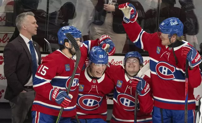 Montreal Canadiens head coach Martin St. Louis looks on as Alex Newhook (15), Juraj Slafkovsky (20), Cole Caufield (13) and Patrik Laine (92) celebrate their win in the final minutes of play against the Carolina Hurricanes during third period NHL hockey action in Montreal on Wednesday, April 16, 2025. (Christinne Muschi/The Canadian Press via AP)