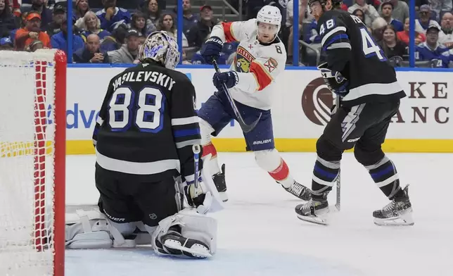 Florida Panthers center Nico Sturm (8) gets off a shot against Tampa Bay Lightning goaltender Andrei Vasilevskiy (88) and defenseman Nick Perbix (48) during the first period of an NHL hockey game Tuesday, April 15, 2025, in Tampa, Fla. (AP Photo/Chris O'Meara)