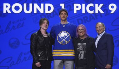 Radim Mrtka, middle left, stands between The Goo Goo Dolls' John Rzeznik, left, and Robby Takac, middle right, and NHL commissioner Gary Bettman after being drafted by the Buffalo Sabres during the NHL hockey draft Friday, June 27, 2025, in Los Angeles. (AP Photo/Damian Dovarganes)