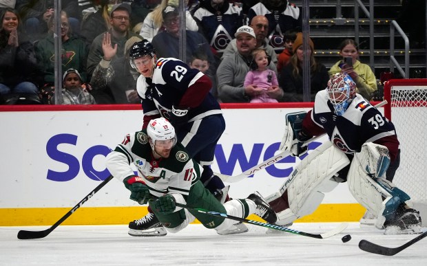 Minnesota Wild left wing Marcus Foligno, front left, passes the puck as Colorado Avalanche center Nathan MacKinnon, back left, and goaltender Mackenzie Blackwood defend in the first period of an NHL hockey game Monday, Jan. 20, 2025, in Denver. (AP Photo/David Zalubowski)